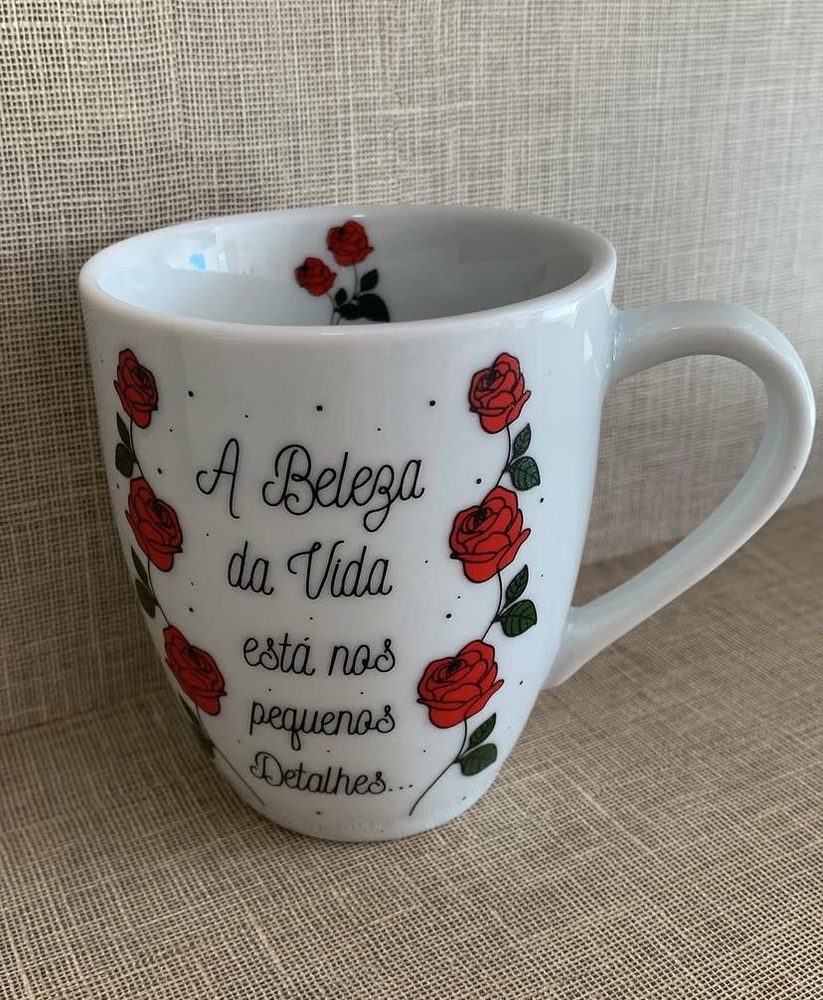 Caneca branca formato tulipa com rosas vermelhas e a frase A beleza da vida está nos pequenos detalhes