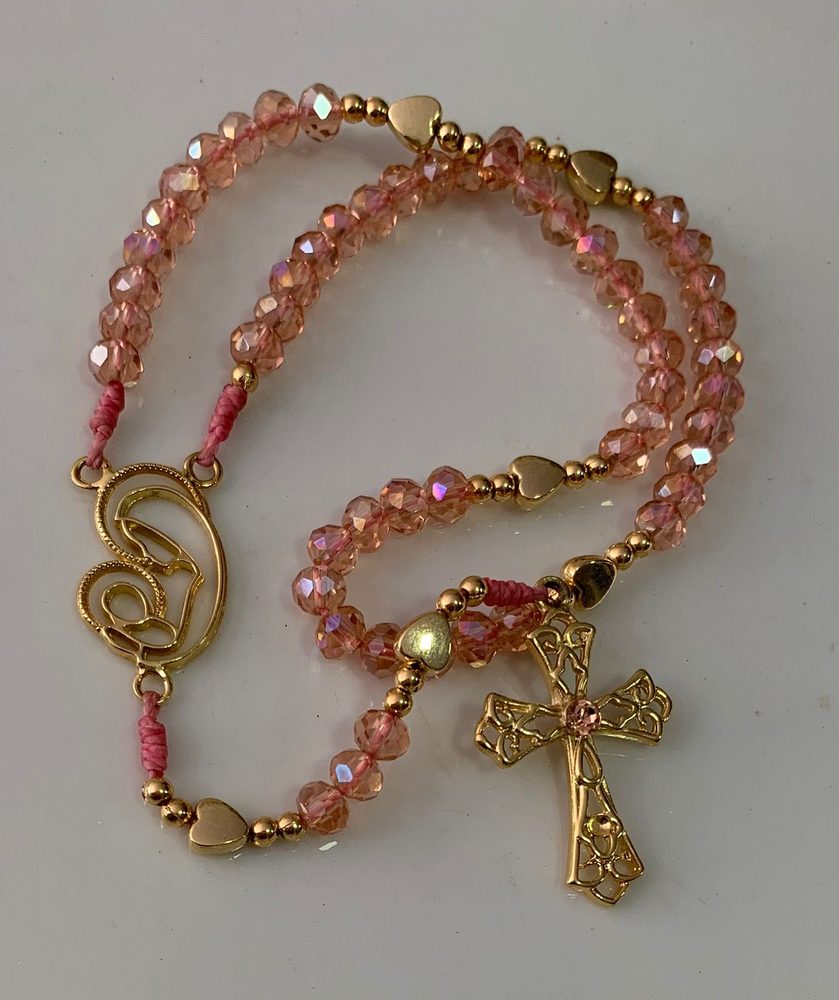Terço de cristais rosa com corações dourados e medalha vazada de Nossa Senhora com o Menino
