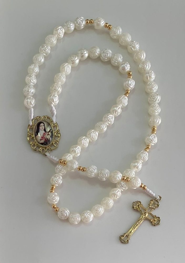 Terço de contas peroladas em formato de rosa com medalha dourada de Santa Terezinha